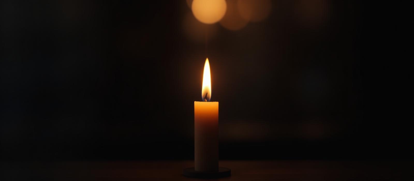 A single candle glowing in a calm dark room